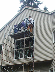 Installing a new residential window on top of a scaffold